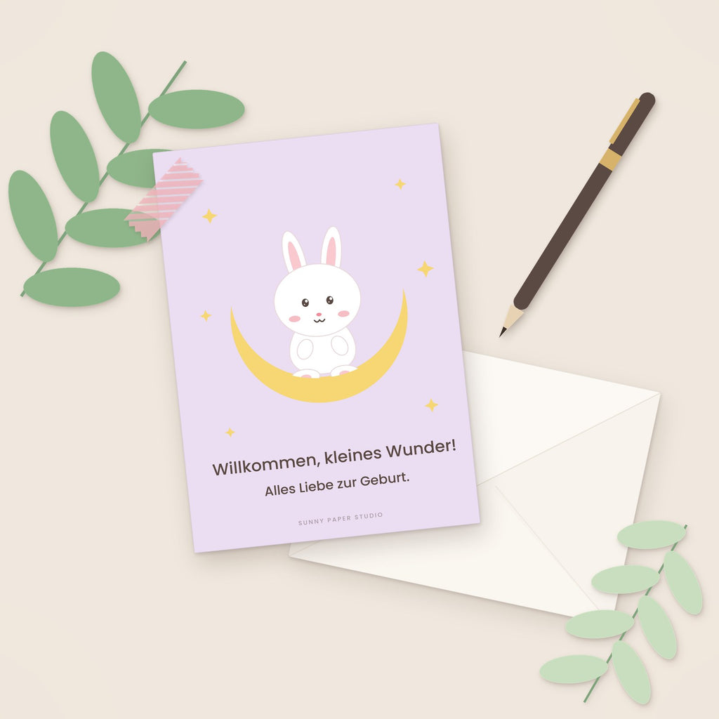 Glückwunschkarte zur Geburt Hase im Mond auf dem Schreibtisch mit Stift